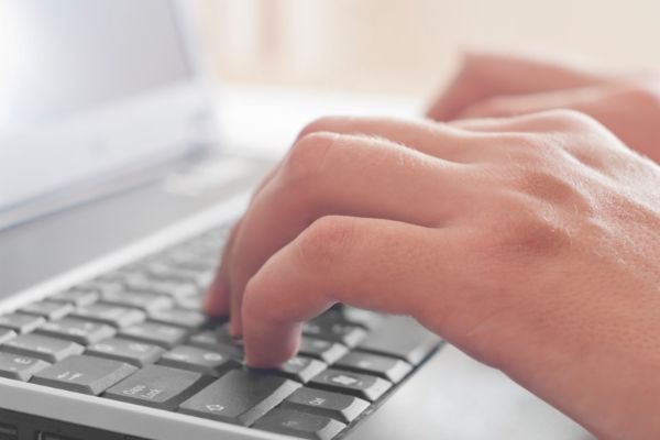 Finger tippen in die Tastatur eines Notebooks